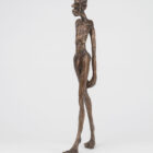 Bronzeskulptur „Feminist“ von Tim David Trillsam, 50 cm hoch, mit überlängter, gehender Männerfigur und stilisiertem Irokesenschnitt.