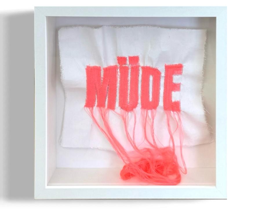 claudia_simon_pop_art_living_room Claudia Simon „Müde“, neonrote Wortstickerei auf weißer Leinwand mit langen losen Fäden in einem weißen Objektrahmen.