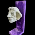 Dennis Thies, „Kopf“, helle Kopfskulptur auf violettem Trägerelement, Mischtechnik, Unikat, 30 × 10 cm, 2006